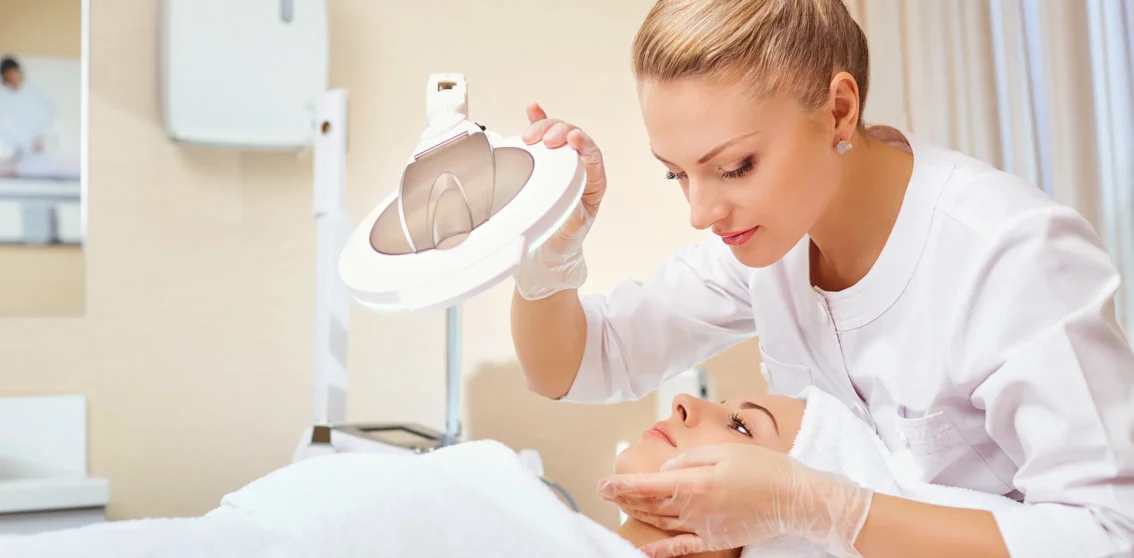 beauty therapists inspecting female clients for blemishes and problem areas of face during facial treatment