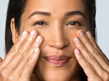 asian woman massaging facial oil into cheeks